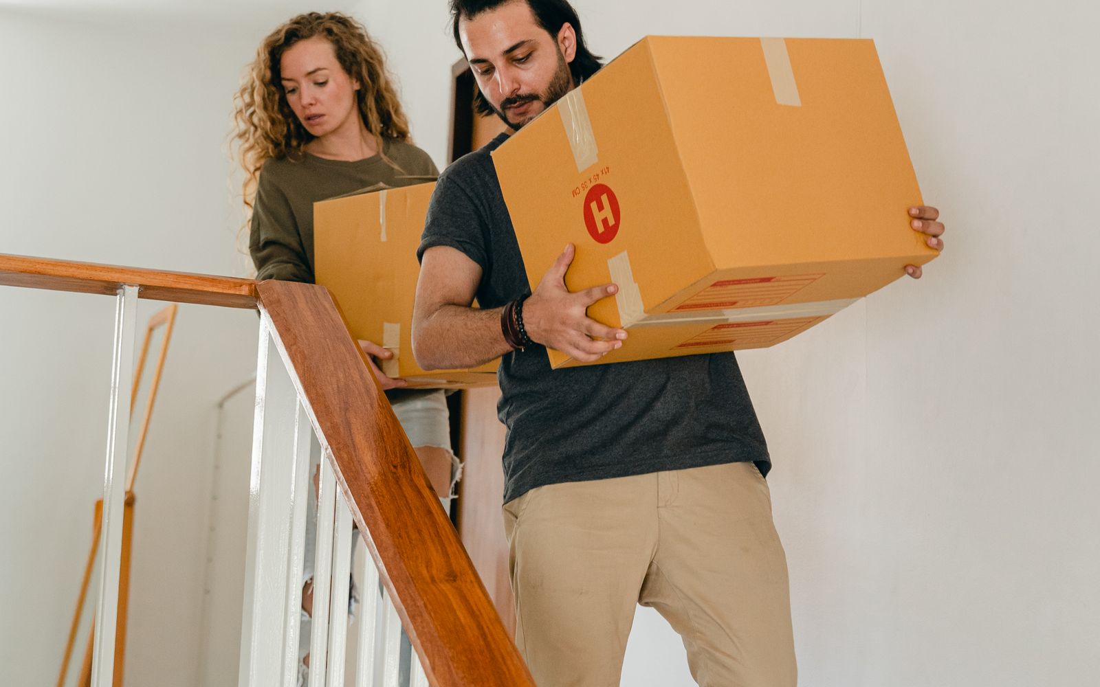 A couple carrying moving boxes into their new home