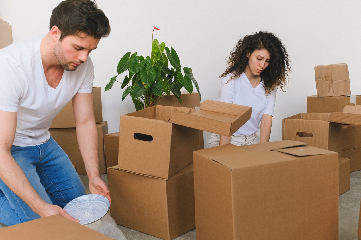 A couple carefully packing fragile items into moving boxes